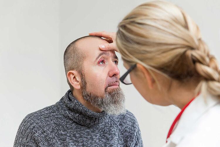 Augenärztin untersucht Auge eines Patienten.